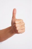 Close-up of hand indicating thumbs up against white background