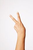 Close-up of hand indicating peace sign against white background