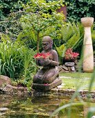Balinese stone statue of woman kneeling in water pool