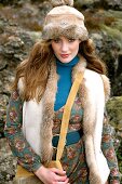 Beautiful woman with red long hair wearing fur cap and fur vest, smiling