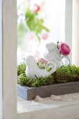 Porcelain figures with flowers on tray with moss