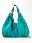 Close-up of turquoise suede handbag with tassel on white background