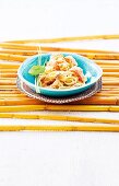 Fettuccine with shrimp and asiago cheese in blue bowl placed on bamboo sticks