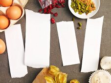 Four blank pieces of paper surrounded by ingredients for muffins