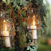Two lit candles in glass jar with ivy