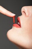 Frauengesicht, Profil, rote Lippen, Lipgloss tropft v.Finger auf Mund
