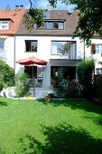 Facade of house with white exterior, window, terrace and garden