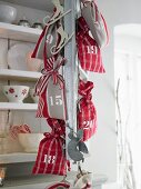 Rot-weiße Säckchen als Adventskalender an Metallkette hängend