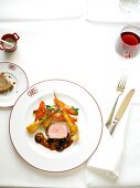 Roti of veal with hazelnuts, cherry sauce and vegetables on dish
