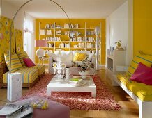 View of white and yellow painted room with sofa, chair, table, carpet and shelf