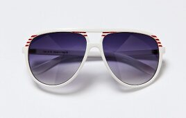 Close-up of sunglasses in pilot style with white-red stripes on white background