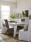 Dining room with wicker furniture, white slipcovers and picture gallery on wall