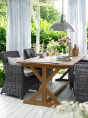 Wooden dining table with wicker chairs on terrace