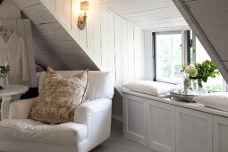White arm chair with pillow in attic room