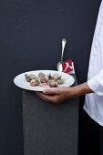 Man's hand holding serving dish with mussels, lemon jelly and oysters herb