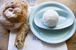 Olive bread and soft cheese ball on saucer, overhead view