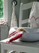 Waschschüssel auf Stuhl mit Wasch- handschuh, Handtücher, Schwamm