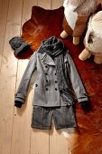 Grey short coat, scarf and had on wooden floor