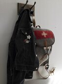 Jacket and backpack with sewn emblem alpine motifs hanging on wall