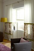 White fabric curtains with pattern and yellow floor lamp