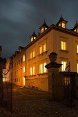 An old town house by night with illuminated windows and gables