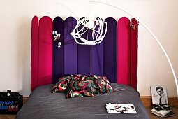 Modern bed with multi-coloured headboard made of foldable wooden panels