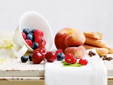 An arrangement of fresh fruit, sponge fingers and coffee beans