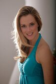 Portrait of beautiful blonde woman wearing green halter top, smiling