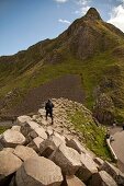 Man walking on Giant's Causeway overlooking mountain at Antrim coast, Ireland