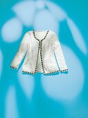 White crochet cardigan with DIY jewels on blue background