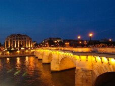Illuminated Pont Neuf bridge over Seine river at evening in Paris, France
