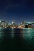 View of Brooklyn Bridge on East River at night in Manhattan, New York, USA