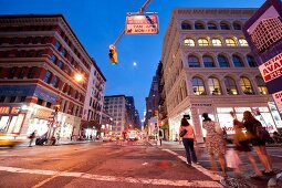 Low angle view of people at Broadway in SoHo at night, New York, USA