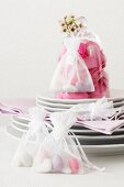 Organza bag with wedding almonds on stack of plates