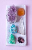 Overhead view of various gemstones used for therapy on purple background