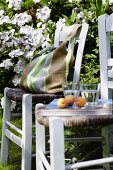 Striped garden bag with glass of water and fruits on chair in garden