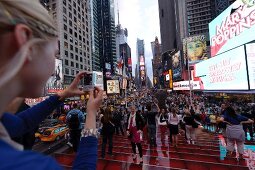 Woman photographing her friend at Times Square in New York, USA