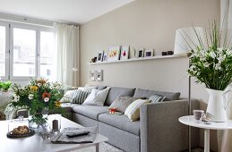 Living room with gray sofa, cushions and shelf board