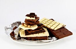 Close-up of different chocolate bars stacked on silver foil on plate