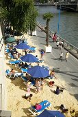 People relaxing on beach beside Seine river in Paris, France