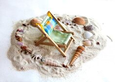 Liegestuhl in einem Herz aus Muscheln im Sand