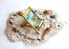 Deck chair in center of heart made of sea shells on sand