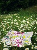 A floral patterned blanket lying on flowery meadow
