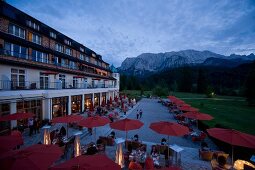 People sitting in terrace of Hotel Schloss Elmau at dusk, Upper Bavaria, Germany