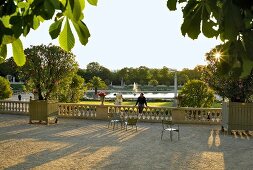 Tourists relaxing near water in Tuileries Garden in front of Roue de Paris, Paris, France