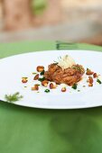 Milk sweetbread with parsley, chanterelles and spruce tips on plate