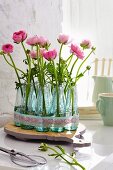 Ranunculus in several miniature bottles used as vases