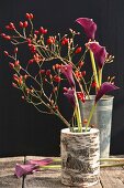 Mini-Hagebutten und violette Calla in einer Vase aus Birkenholz