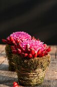 Hagebutten und Pompondahlien in Vasen aus Naturmaterialien