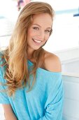 Portrait of beautiful blonde woman wearing turquoise top, smiling